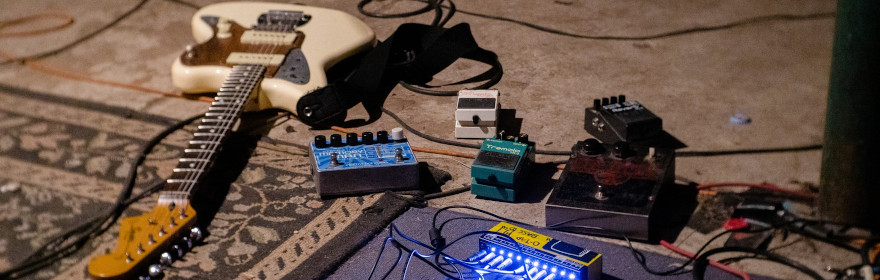 guitar lying on stage with effects pedals